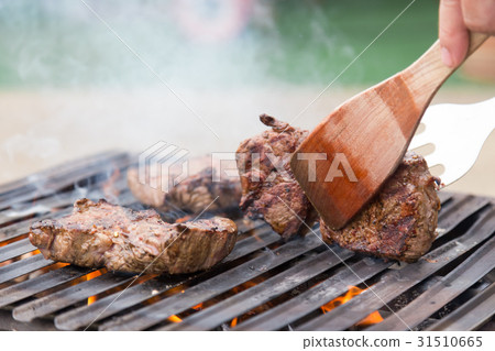 Chef grilling beef steaks on open flame BBQ. Chef grilling beef steaks on open flame BBQ. 31510665