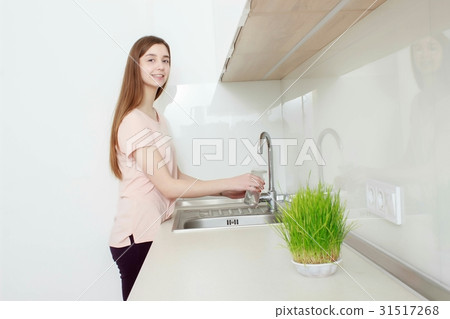 Woman Pouring Glass Of Water From Tap In Kitchen Woman Pouring Glass Of Water From Tap In Kitchen 31517268