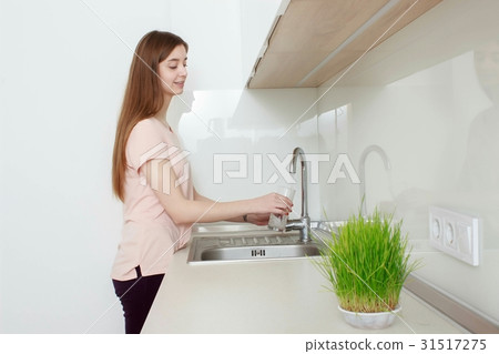 Woman Pouring Glass Of Water From Tap In Kitchen Woman Pouring Glass Of Water From Tap In Kitchen 31517275