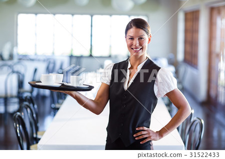 Portrait of smiling waitress holding a tray of coffee cups 31522433