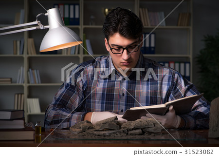 Archeologist working late night in office 31523082