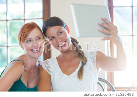 Two beautiful women taking selfie with digital tablet Two beautiful women taking selfie with digital tablet 31523498