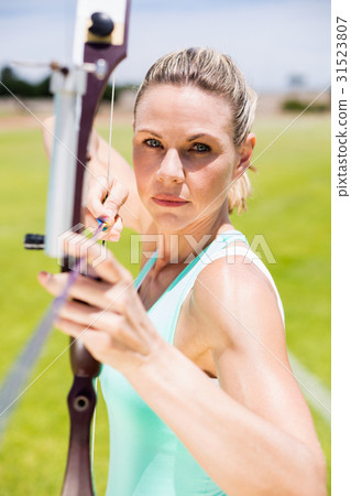 Confident female athlete practicing archery Confident female athlete practicing archery 31523807