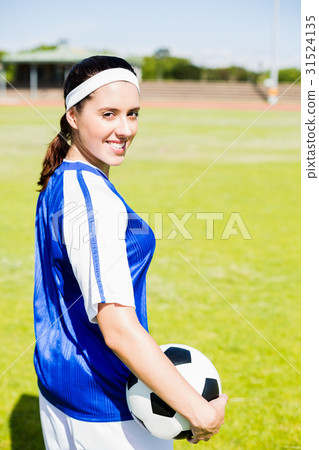 Happy soccer player standing with a ball 31524135