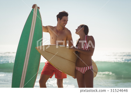 Couple standing with surfboard on beach 31524646