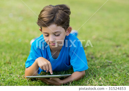 Young boy using digital tablet in park 31524853