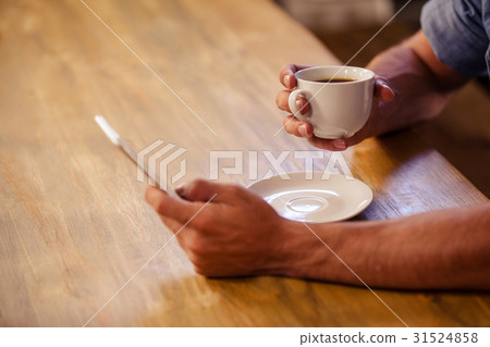 Cropped image of hipster man using smartphone while drinking cup of coffee Cropped image of hipster man using smartphone while drinking cup of coffee 31524858