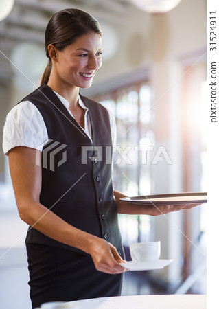 Smiling waitress serving cup of coffee 31524911