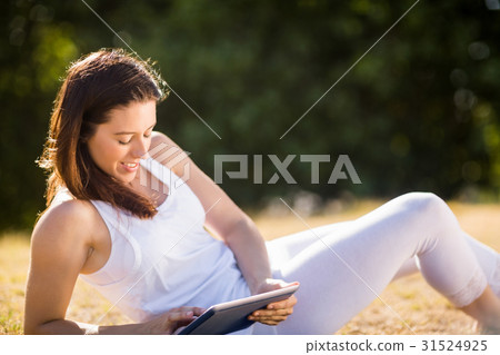 Woman sitting on grass and using digital tablet 31524925