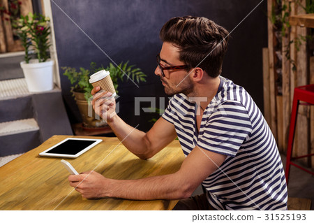Young man looking at disposable cup in cafeteria 31525193