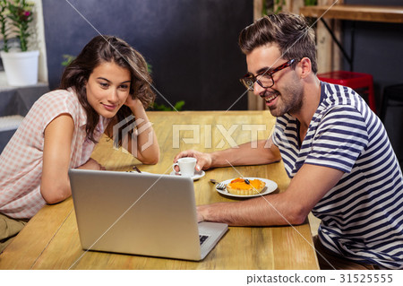 Young couple using laptop in cafeteria Young couple using laptop in cafeteria 31525555