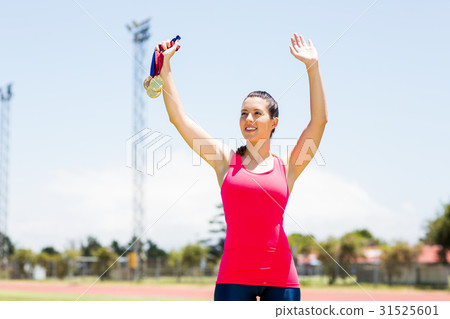Female athlete waving her hand and showing gold medal Female athlete waving her hand and showing gold medal 31525601