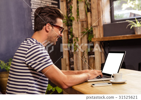 Young man using laptop in cafeteria Young man using laptop in cafeteria 31525621