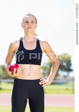 Confident female athlete holding a shot put ball Confident female athlete holding a shot put ball 31525623