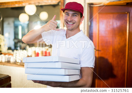 Pizza delivery man holding pizza boxes making a phone gesture Pizza delivery man holding pizza boxes making a phone gesture 31525761