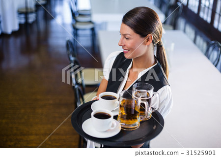 Waitress holding serving tray with coffee cup and pint of beer 31525901
