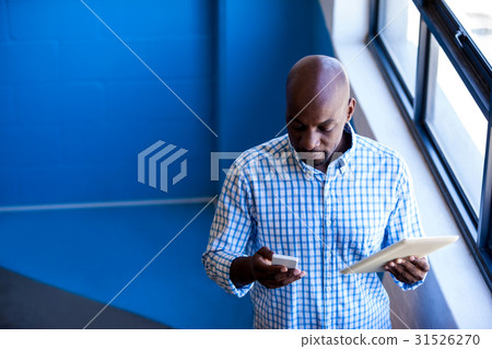 Casual businessman holding a mobile phone and tablet computer Casual businessman holding a mobile phone and tablet computer 31526270