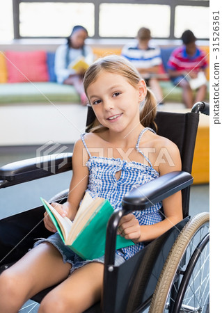 Portrait of disabled school girl reading book in library Portrait of disabled school girl reading book in library 31526361