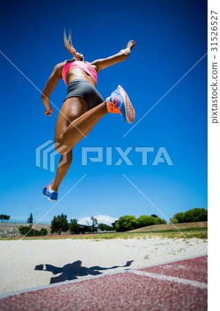 Female athlete performing a long jump Female athlete performing a long jump 31526527