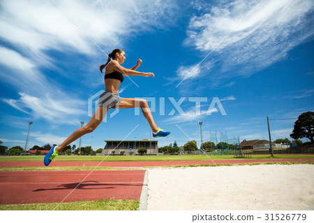 Female athlete performing a long jump Female athlete performing a long jump 31526779