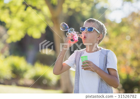 Young boy blowing bubbles through bubble wand Young boy blowing bubbles through bubble wand 31526782