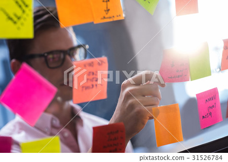Hipster reading a post it on a window Hipster reading a post it on a window 31526784