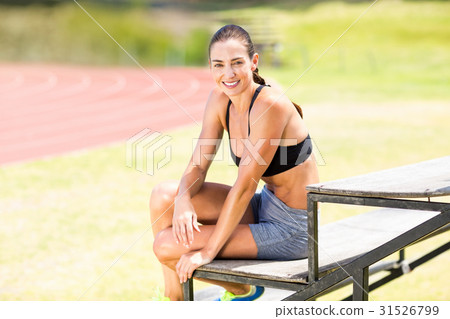 Portrait of happy female athlete sitting on stand 31526799