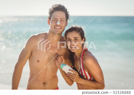 Young couple with sunscreen lotion on beach 31526888