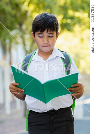 Happy schoolboy reading book in campus Happy schoolboy reading book in campus 31527056
