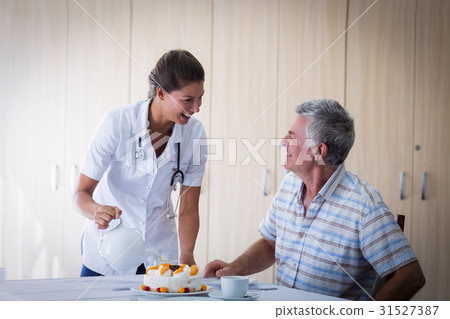 Female doctor celebration seniors man birthday in living room Female doctor celebration seniors man birthday in living room 31527387
