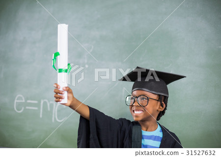 Excited schoolboy in mortar board holding certificate in classroom 31527632