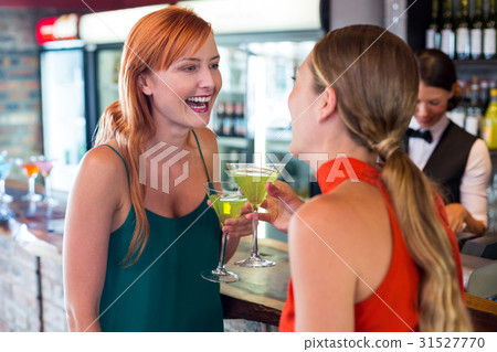 Happy friends holding a cocktail in front of bar counter 31527770