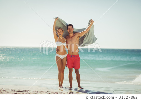 Couple holding towel on beach 31527862