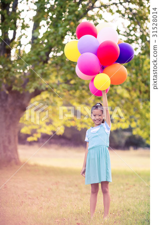 Portrait of smiling girl holding balloons in park Portrait of smiling girl holding balloons in park 31528014