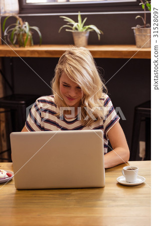 Woman using a laptop sitting on a desk 31528097
