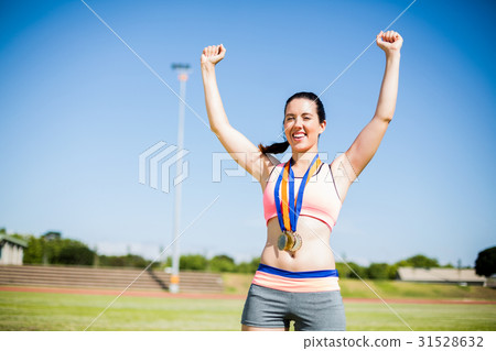 Excited female athlete with gold medals around her neck Excited female athlete with gold medals around her neck 31528632