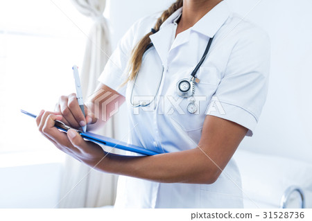 Female doctor writing on clipboard in hospital Female doctor writing on clipboard in hospital 31528736