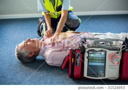 Paramedic using an external defibrillator on an unconscious patient Paramedic using an external defibrillator on an unconscious patient 31528953