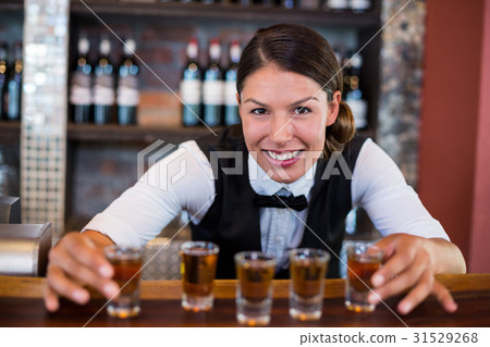 Portrait of bartender placing shot glasses on bar counter 31529268