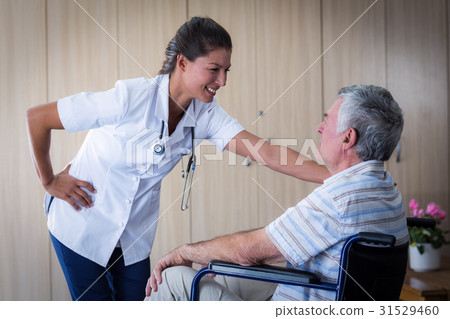 Happy senior man and doctor interacting in living room Happy senior man and doctor interacting in living room 31529460