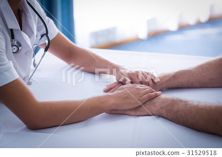 Mid section of female doctor consoling senior man in living room Mid section of female doctor consoling senior man in living room 31529518