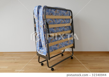 A folding bed in front of a white wall 31540944