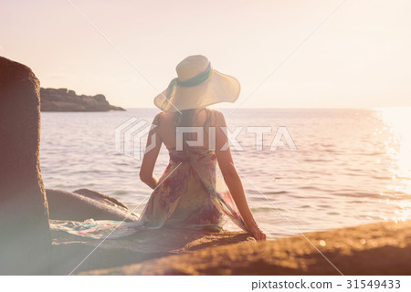 Women is sitting on a rock on the beach Women is sitting on a rock on the beach 31549433