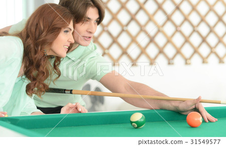 young couple playing billiard young couple playing billiard 31549577