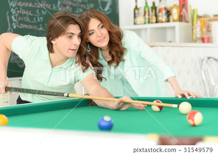 young couple playing billiard young couple playing billiard 31549579