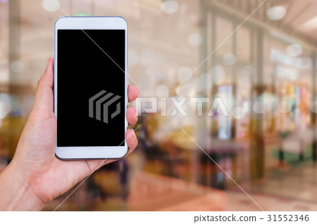 hand holding mobile phone with blur cafe hand holding mobile phone with blur cafe 31552346
