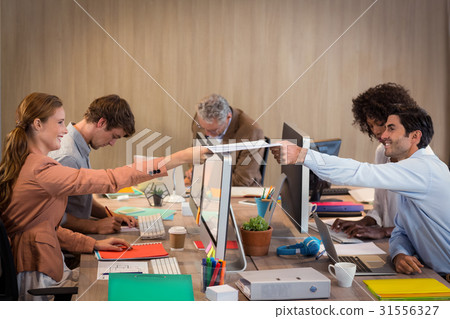 Businessman passing a file to his colleague 31556327