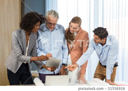 Businesswoman and coworker discussing blueprint on the desk using digital tablet Businesswoman and coworker discussing blueprint on the desk using digital tablet 31556916