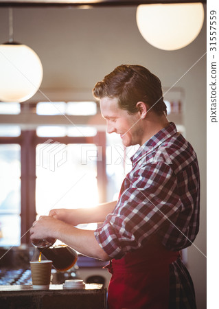 Smiling waiter pouring a cup of coffee 31557559
