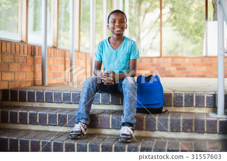 Smiling schoolboy sitting on staircase Smiling schoolboy sitting on staircase 31557603